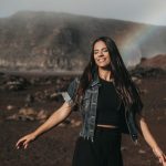 Woman smiling and happy in front of a rainbow at Volcano